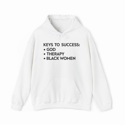 The Keys To Success Hoodie by Illegal Shirts is a white cotton-polyester blend with black text: KEYS TO SUCCESS: • GOD • THERAPY • BLACK WOMEN. It features a front pocket and is displayed on a plain white background.