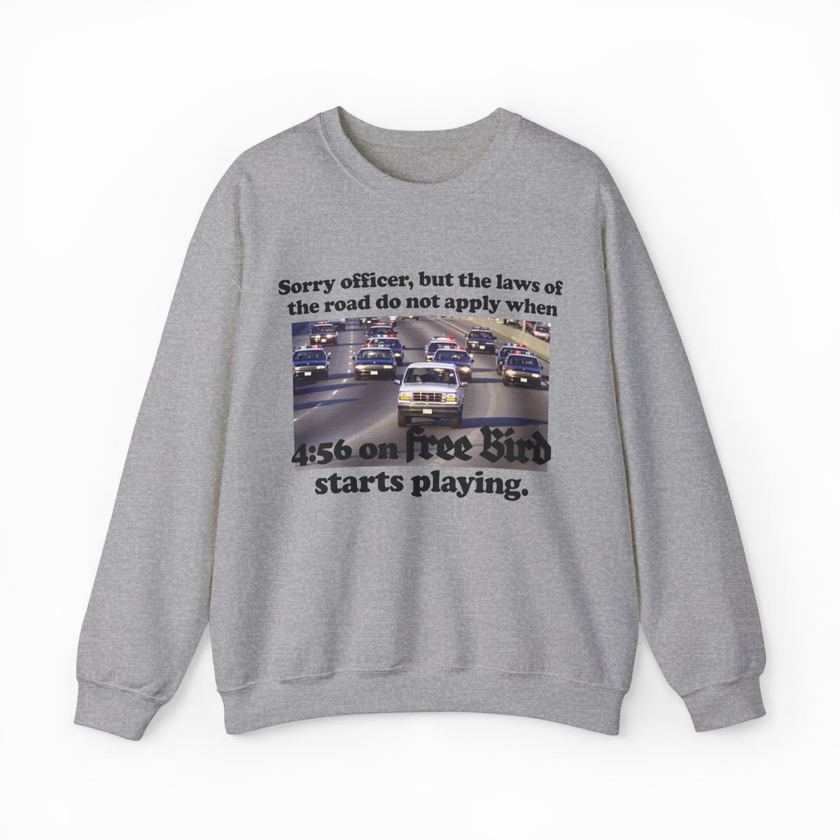 The O.J. Simpson Free Bird Crewneck features a gray design with cars on a highway and the caption: Sorry officer, but the laws of the road do not apply when 4:56 on Free Bird starts playing—ideal for fans of humor and classic rock.