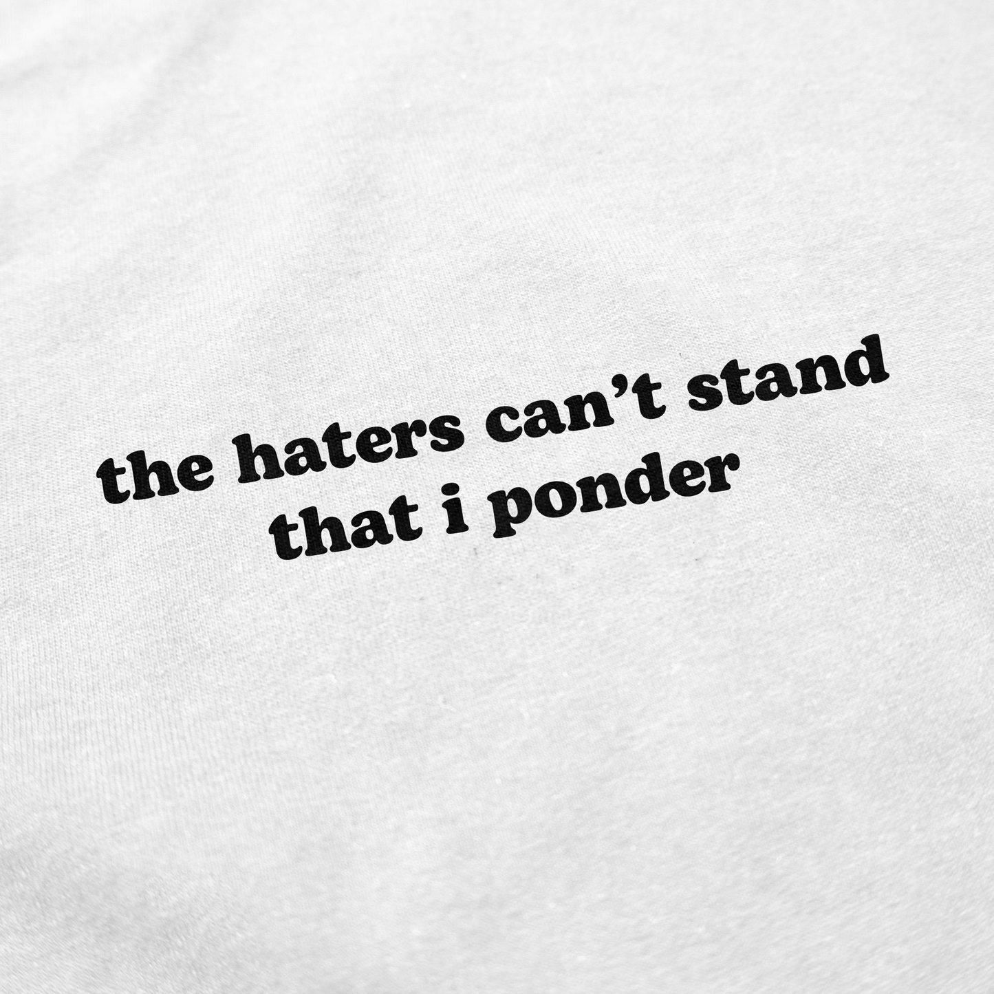 The Haters Can't Stand That I Ponder T-Shirt features white fabric with bold black text and a rounded font—ideal for fans of witty, statement shirts who want to add personality to their wardrobe.
