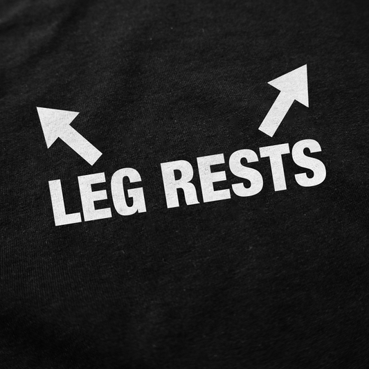 White text on black fabric reads "LEG RESTS" with two white arrows pointing up and outward. The Leg Rests T-Shirt is a standout piece for fans of unique, funny shirts.