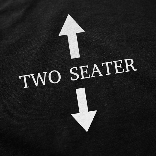 The Two Seater T-Shirt features “TWO SEATER” in white text between two large vertical arrows, printed on black cotton fabric.