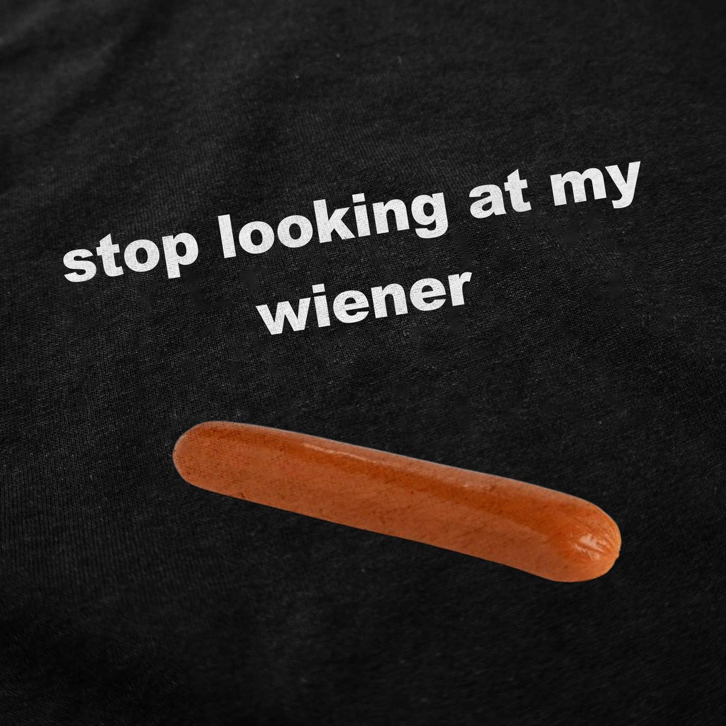 The Stop Looking At My Wiener T-Shirt is a black cotton tee with “stop looking at my wiener” in white letters above a hot dog graphic—perfect for fans of quirky shirts.