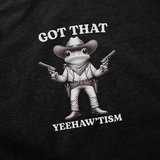 The Got That Yeehaw'Tism T-Shirt features a cartoon cowboy frog with pistols and the phrase "GOT THAT YEEHAW’TISM" on a black background—a bold, funny shirt for anyone who loves unique cowboy style.
