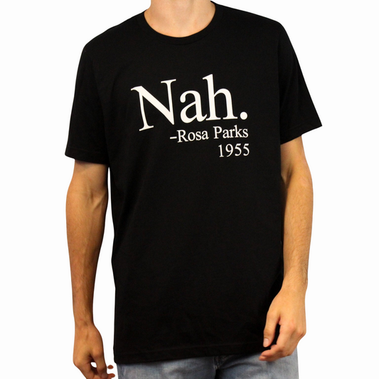 A person wears the Nah. T-Shirt, crafted from ethically grown cotton and displaying “Nah. – Rosa Parks 1955” in white text on the front. The person’s head is partially out of frame.