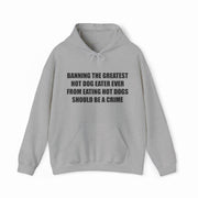 The “Banning The Greatest Hot Dog Eater Ever From Eating Hot Dogs Should Be A Crime Hoodie” features black text on gray—perfect for fans of funny hot dog shirts or anyone who loves humorous, bold statement apparel.