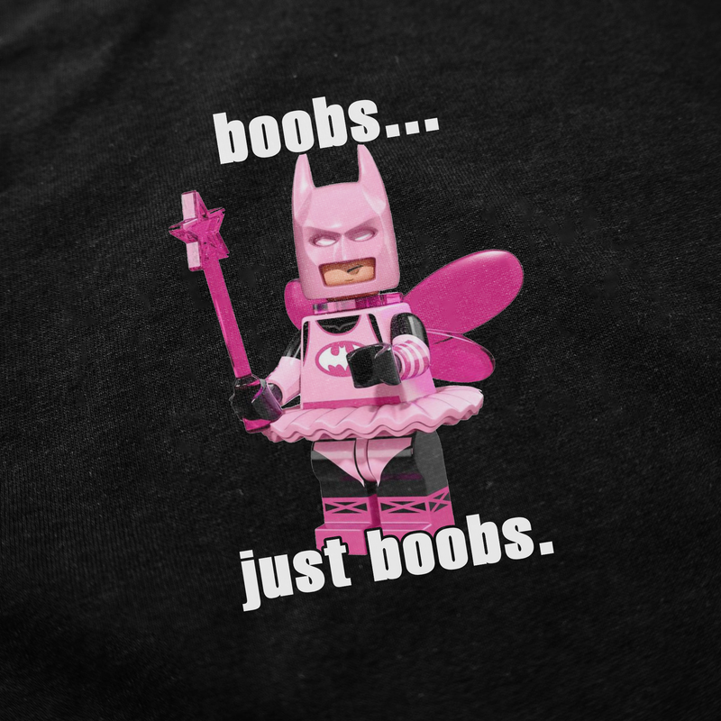 The Boobs... Just Boobs. T-Shirt features a quirky pink Batman minifigure in a tutu, fairy wings, and holding a wand on a black background—perfect for fans of playful, funny shirts or anyone seeking a bold statement tee.