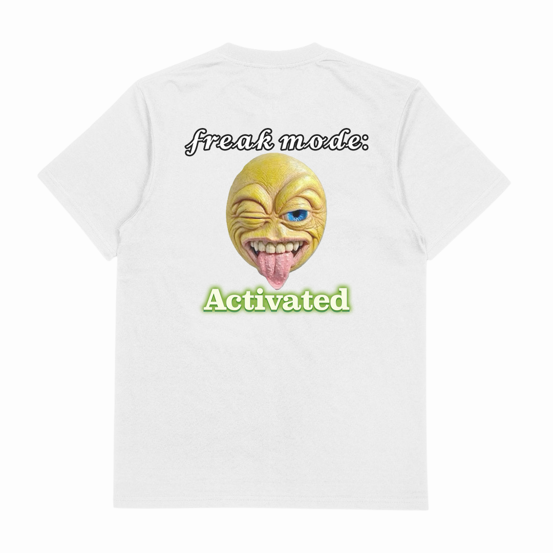 The Freak Mode Activated T-Shirt (Backprint) is a white, 175 GSM, ethically grown cotton tee featuring a yellow cartoon face with a mischievous grin and tongue out, "freak mode:" above and "Activated" in green below.