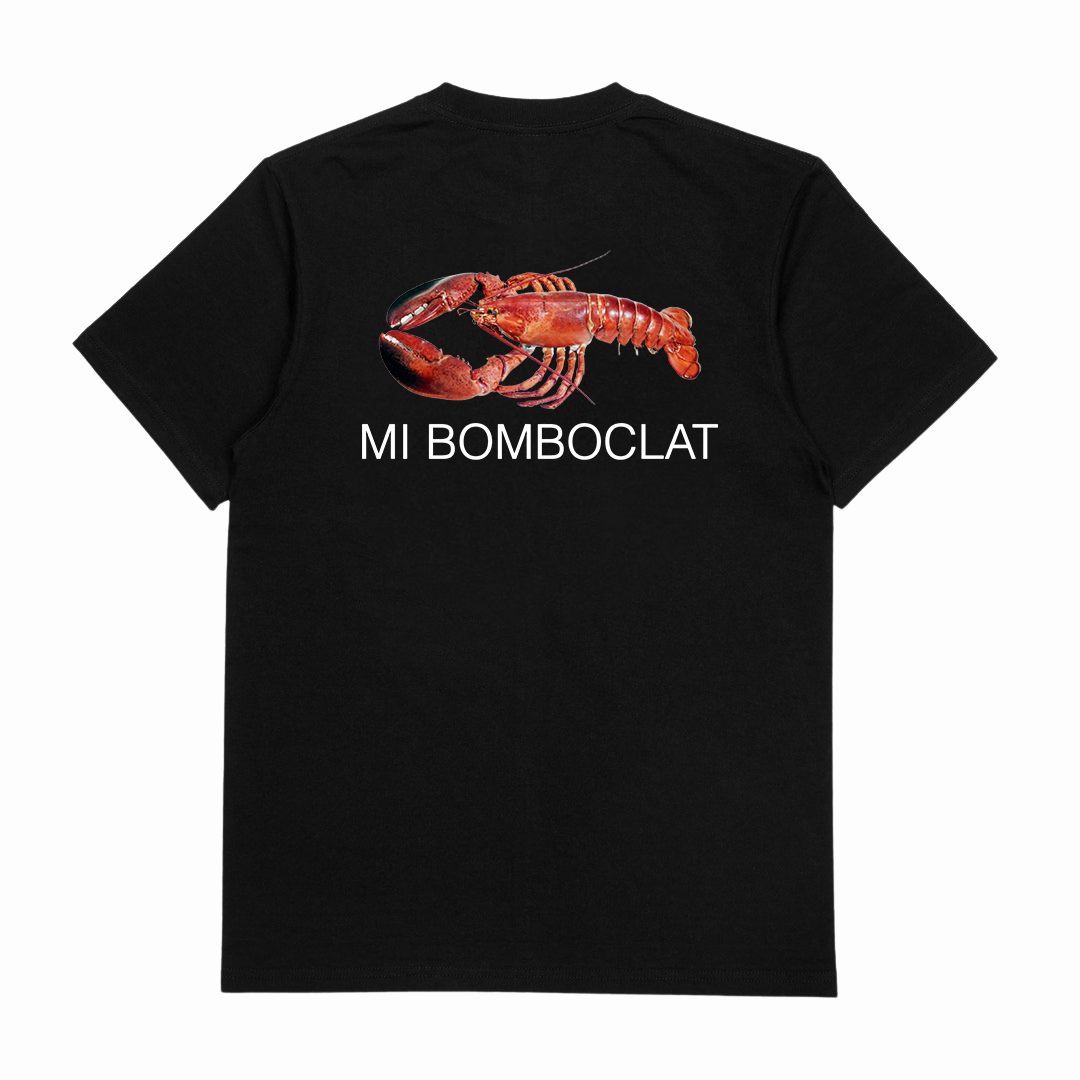 The Mi Bomboclat T-Shirt (Backprint) is a black cotton tee with a large red lobster graphic and "MI BOMBOCLAT" in white beneath it on the back. Made from ethically grown materials and finished with a durable double seam.