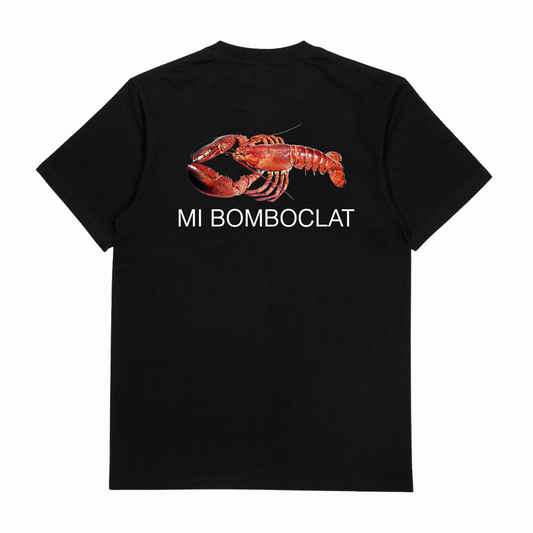 The Mi Bomboclat T-Shirt (Backprint) is a black cotton tee with a large red lobster graphic and "MI BOMBOCLAT" in white beneath it on the back. Made from ethically grown materials and finished with a durable double seam.