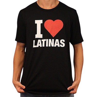 Wearing the I Heart Latinas T-Shirt, a person poses holding the sides of this black tee, which features bold white and red "I ♥ LATINAS" text across the front. It’s made from ethically grown cotton.