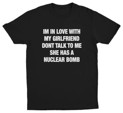 Black crew neck t-shirt with white text that reads: 'I'M IN LOVE WITH MY GIRLFRIEND DON'T TALK TO ME SHE HAS A NUCLEAR BOMB'.
