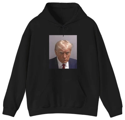 The Trump Mug Shot Hoodie is a black hoodie featuring a printed photo of a blond man in a suit and tie with a serious expression, and includes a tear-away label for added comfort.