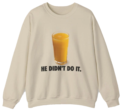 The He Didn't Do It Crewneck is a beige sweatshirt with a glass of orange juice above bold black text—ideal for fans of funny shirts or anyone seeking unique Illegal Shirts with a playful twist.