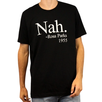 A person wears the Nah. T-Shirt, crafted from ethically grown cotton and displaying “Nah. – Rosa Parks 1955” in white text on the front. The person’s head is partially out of frame.