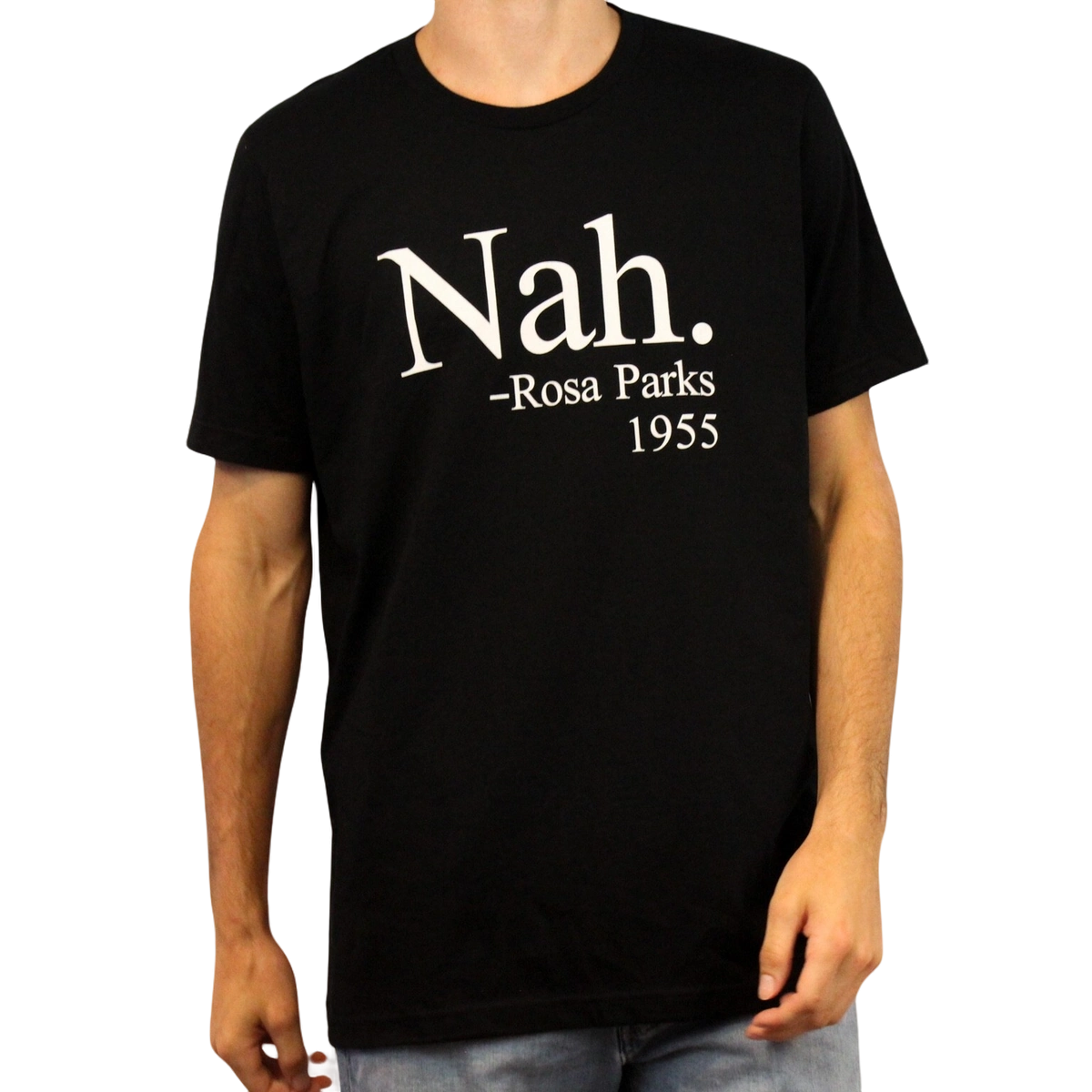 A person wears the Nah. T-Shirt, crafted from ethically grown cotton and displaying “Nah. – Rosa Parks 1955” in white text on the front. The person’s head is partially out of frame.