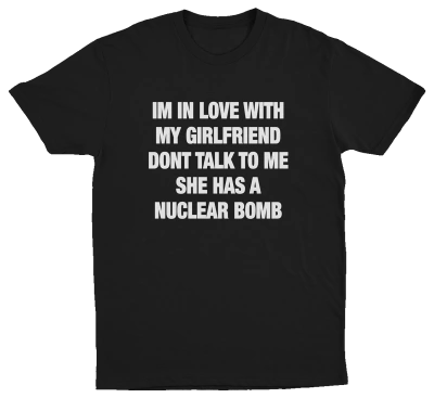 Black crew neck t-shirt with white text that reads: 'I'M IN LOVE WITH MY GIRLFRIEND DON'T TALK TO ME SHE HAS A NUCLEAR BOMB'.