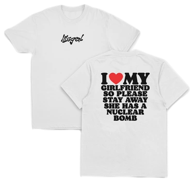 The "I Heart My Girlfriend So Please Stay Away She Has A Nuclear Bomb T-Shirt (Backprint)" is a white, 175 GSM cotton tee with "Illegal" in black on the front and bold text on the back. Ethically grown cotton ensures comfort and sustainability.
