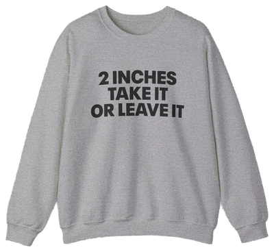 The 2 Inches Take It Or Leave It Crewneck in gray features bold black text on the front and is laid flat on a white background—perfect for anyone who enjoys funny shirts and wants to add humor to their style.