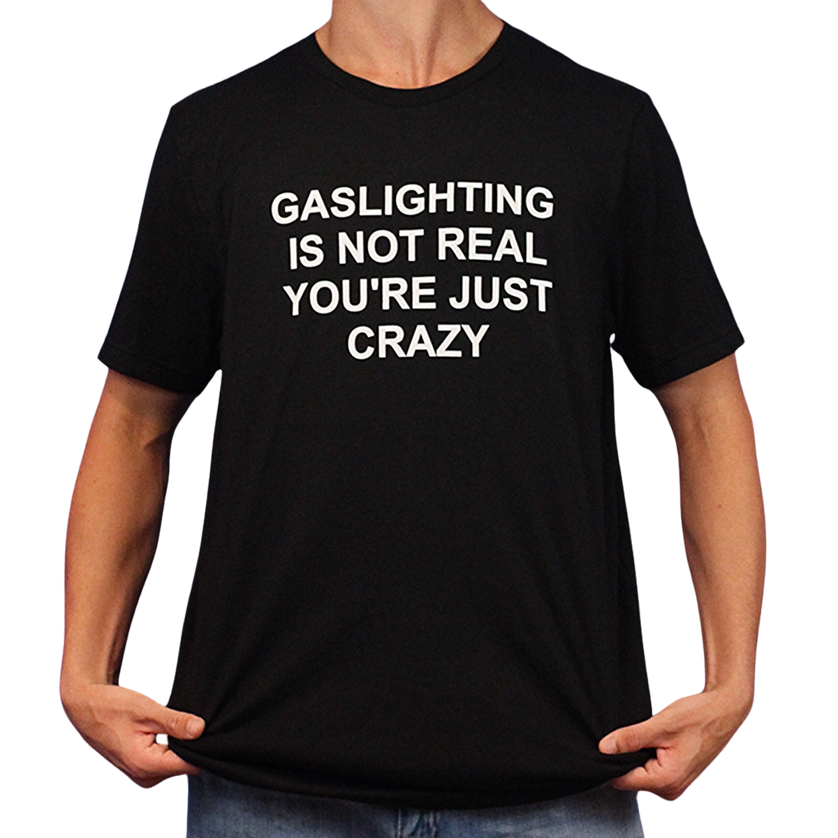 A person holds the sides of a Gaslighting Is Not Real You're Just Crazy T-Shirt, featuring the bold white phrase "GASLIGHTING IS NOT REAL YOURE JUST CRAZY"—perfect for fans of edgy and Illegal Shirts humor.