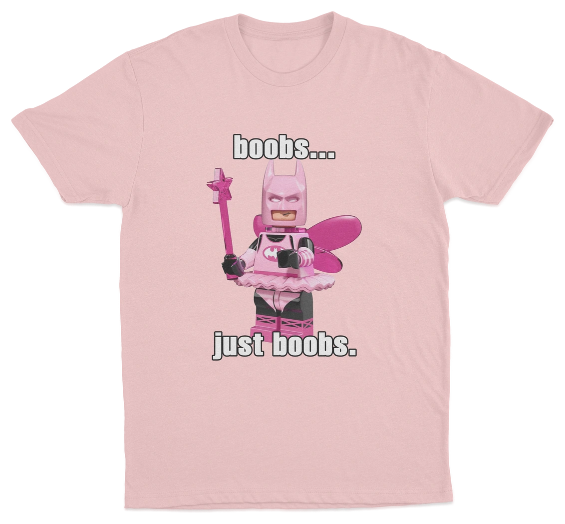 The "Boobs... Just Boobs. T-Shirt" is a pink tee with a LEGO-style Batman in a pink fairy costume, wings, and wand. Features bold text above and below the figure. Ideal for fans of humorous statement shirts!.