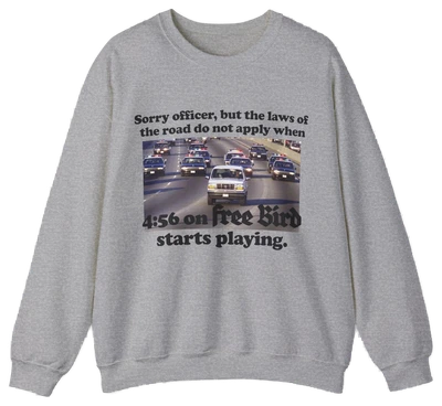 The O.J. Simpson Free Bird Crewneck features a gray design with cars on a highway and the caption: Sorry officer, but the laws of the road do not apply when 4:56 on Free Bird starts playing—ideal for fans of humor and classic rock.